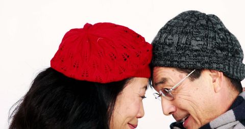 Happy middle-aged couple in winter hats sharing intimate moment