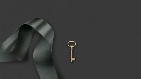 Vintage brass key on gray surface with satin ribbon