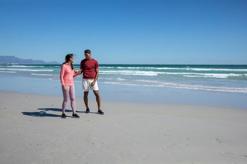 Couple Enjoying Fitness Walk on Sunny Beach Shoreline