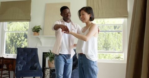 Joyful multicultural couple dancing in cozy living room