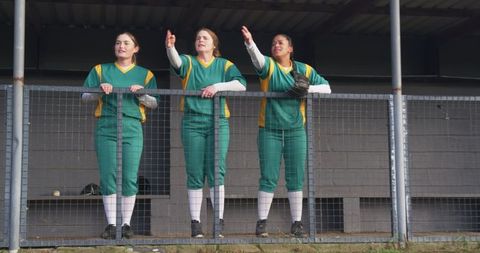 Female softball players at dugout engaging in game strategy