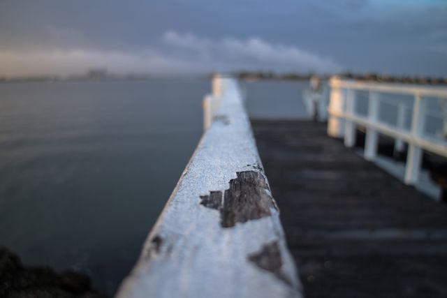 Rustic Wooden Pier Extending Over Tranquil Water under Overcast Sky - Download Free Stock Images Pikwizard.com