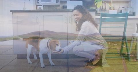 Young woman crouching and petting beagle in cozy kitchen with pastoral landscape overlay