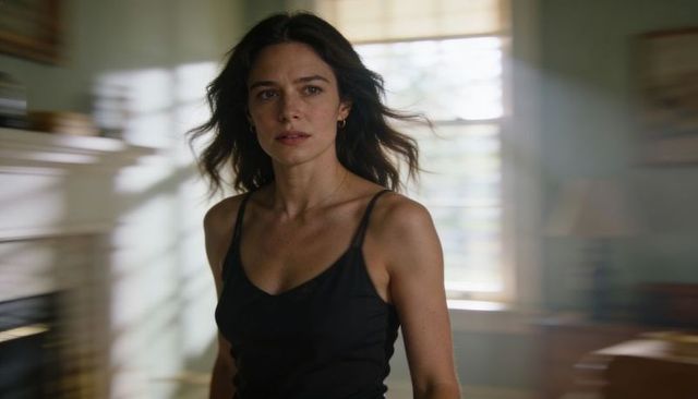 Sunlit woman turning in living room wearing black sleeveless top, motion blur portrait