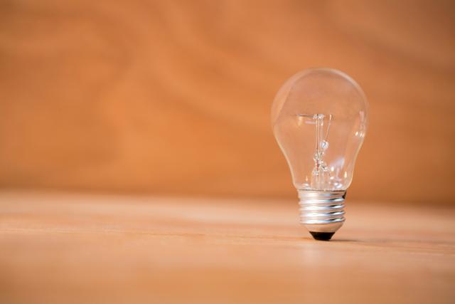 This image of a close-up electric bulb on a wooden surface is ideal for illustrating concepts of energy, innovation, and simplicity. It can be used in articles, presentations, and advertisements related to electricity, lighting solutions, and creative ideas.