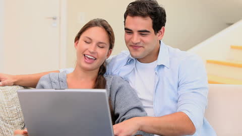 Smiling Couple Enjoying Relaxing Time with Laptop on Sofa