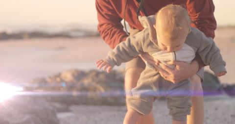 Father Holding Baby at Beach During Golden Hour