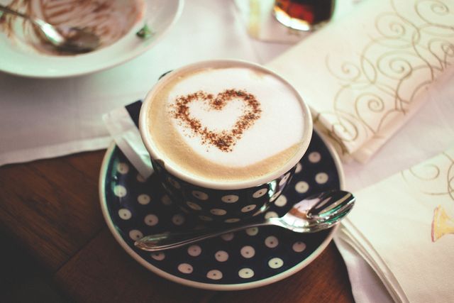 Heart-shaped latte art in polka dot cup on wooden table, perfect for illustrating cozy cafe settings, coffee culture, barista skills, or adding a touch of warmth and love to beverage-focused designs.