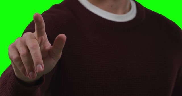 A Caucasian adult male gestures with his index finger extended, with copy space on the green screen background. His gesture could indicate a point of emphasis or the act of pressing an imaginary button.