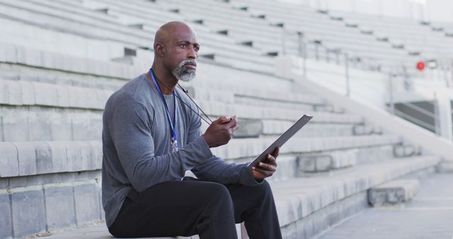 Confident Coach Sitting in Bleachers Holding Clipboard and Whistle - Download Free Stock Images Pikwizard.com