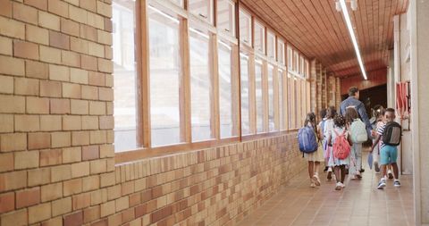 Diverse Schoolchildren with Teacher Walking in Hallway