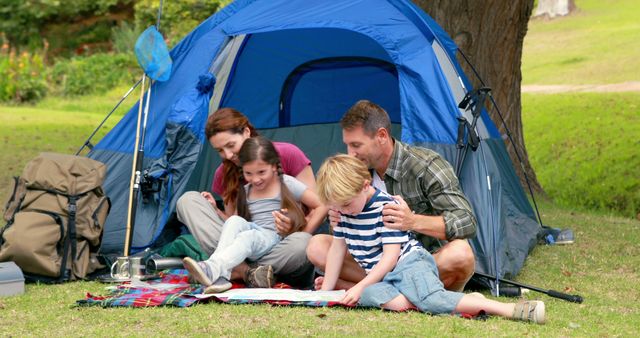 Family enjoying a camping trip in nature surrounded by greenery. Parents and children are spending quality time together outside, making memories. Ideal for promoting family vacations, outdoor adventures, and camping gear.