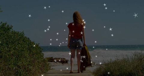 Woman Strolling Towards Ocean on Coastal Boardwalk