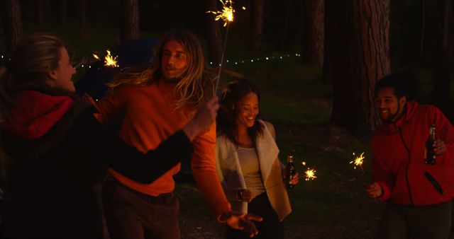 A group of friends celebrating outdoors at night with sparklers, having fun together. Perfect for depicting friendship, outdoor activities, celebrations, parties, and joyful moments in diverse settings.