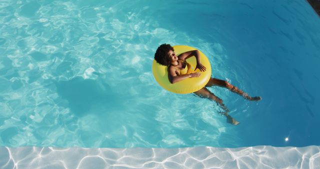 Biracial woman having fun sunbathing on inflatable in swimming pool. hanging out and relaxing outdoors in summer.