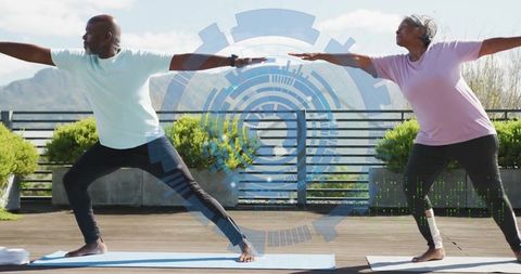 Senior couple practicing yoga warrior ii with digital interface overlay outdoors