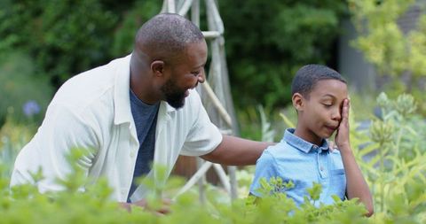 Father comforting son in backyard garden, reassuring child during quiet outdoor moment