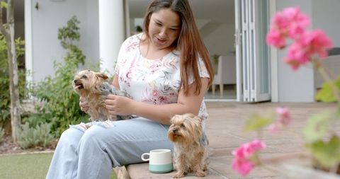 Smiling Woman Relaxing in Garden with Two Yorkshire Terriers
