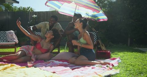 Friends taking selfie during relaxed backyard picnic