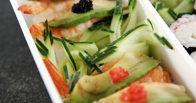 Close-up capture of freshly prepared sushi rolls with shrimp, avocado, and garnishes of cucumber slices. Ideal for illustrating healthy meal choices, Japanese cuisine, food magazines, and gourmet restaurant menus.