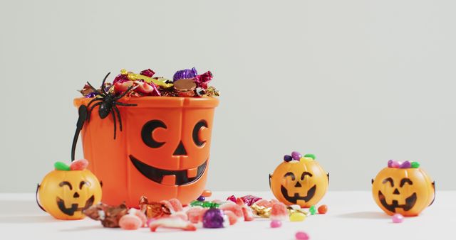 Scary halloween pumpkin printed bucket full of candies against grey background. halloween holiday and celebration concept