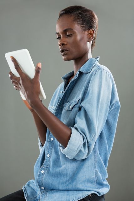 Androgynous man using digital tablet against grey background