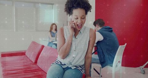 Young woman talking on smartphone while sitting on modern red bench in casual lounge