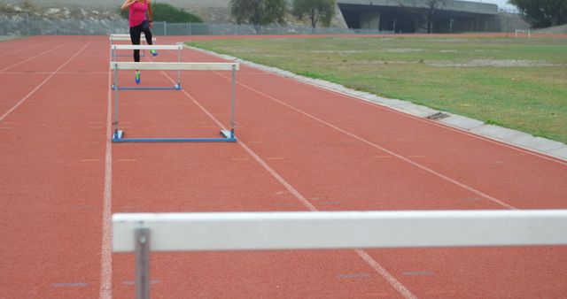 Athlete jumping over hurdles on track field - Download Free Stock Images Pikwizard.com