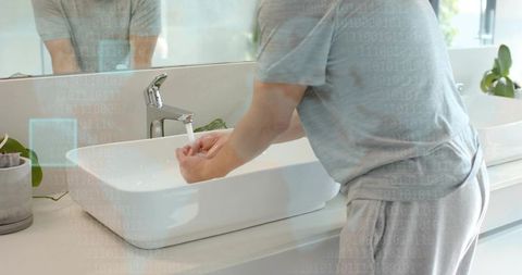 Man washing hands in minimalist modern bathroom with white basin and chrome faucet