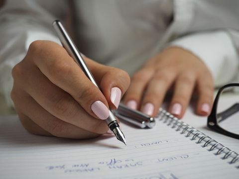 Close-Up of Female Hand Writing in Spiral Notebook with Fountain Pen