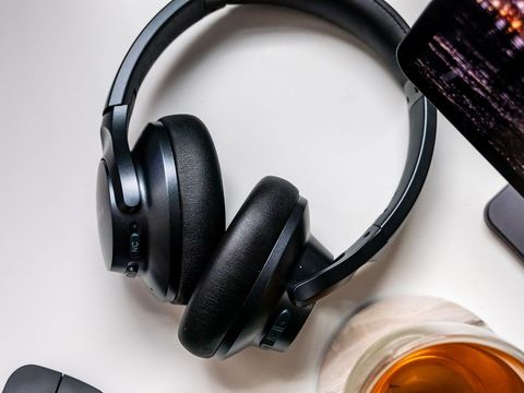 Technology wireless over-ear headphones on desk with beverage