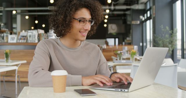 Young Man Working on Laptop in Modern Coffee Shop - Download Free Stock Images Pikwizard.com