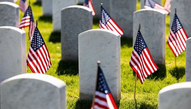 Centered marble headstone with american flags honoring fallen veterans on memorial day