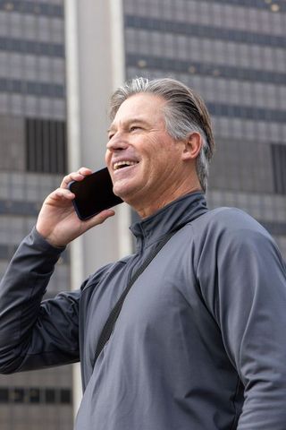 Senior man talking on smartphone in downtown business district smiling and confident