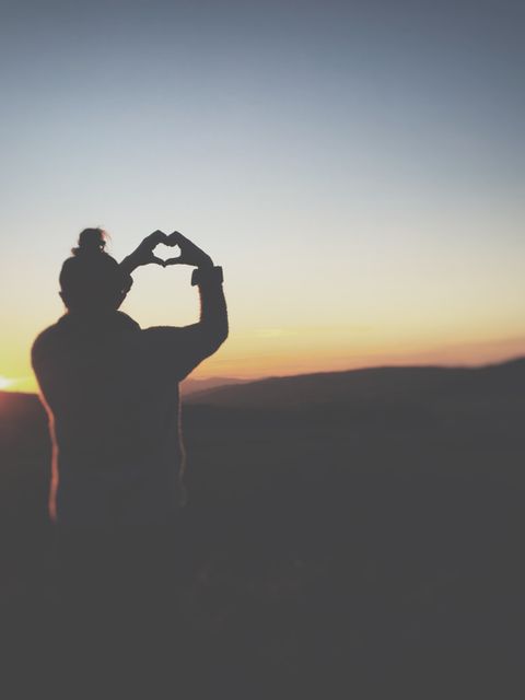 Silhouette of person forming heart with hands during sunset - Download Free Stock Photos Pikwizard.com