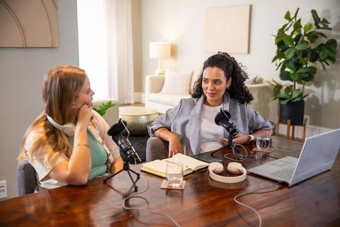 Two female co-hosts recording professional podcast in living room setup