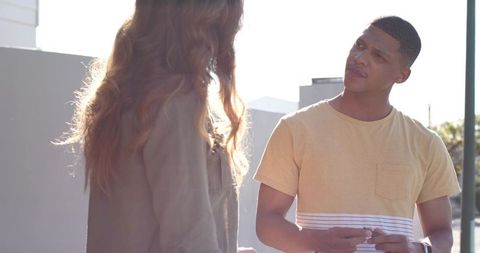 African american friends talking on sunlit rooftop terrace holding keys urban conversation