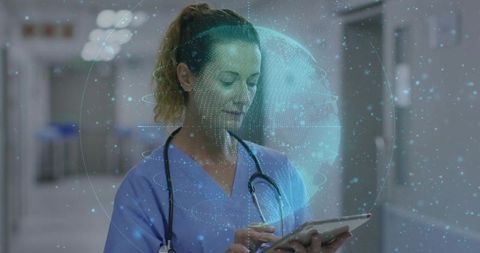 Clinician using tablet with holographic globe and digital health data in hospital corridor