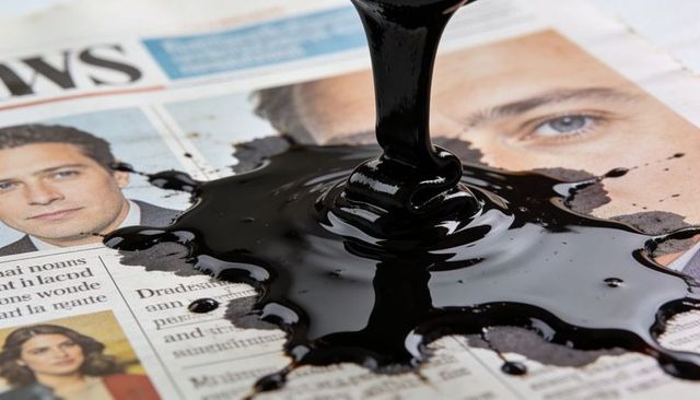 Pouring thick black ink over newspaper portraits causing smear, censorship, media blackout