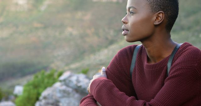Young African American woman enjoys a serene outdoor moment. She appears contemplative while embracing nature's tranquility.