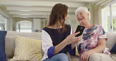 Smiling Women Sharing Smartphone in Cozy Living Room