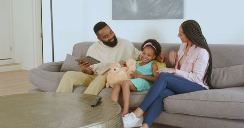 Happy Family Bonding on Sofa with Daughter and Teddy Bear