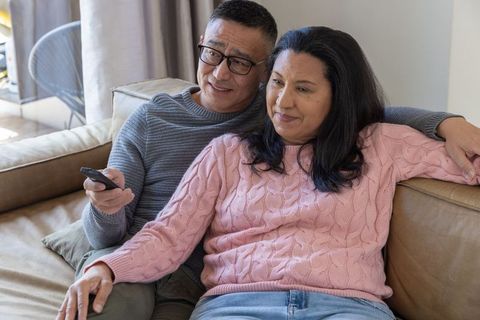 Senior Couple Relaxing on Sofa with TV Remote at Home