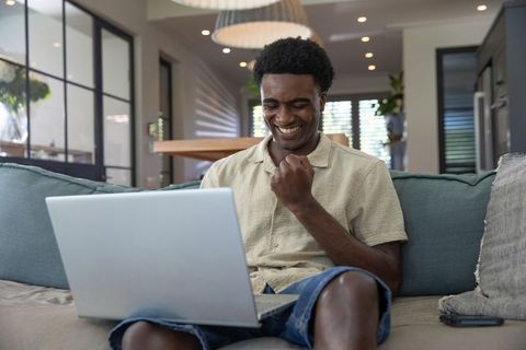 Excited Man Celebrating Success on Laptop at Home