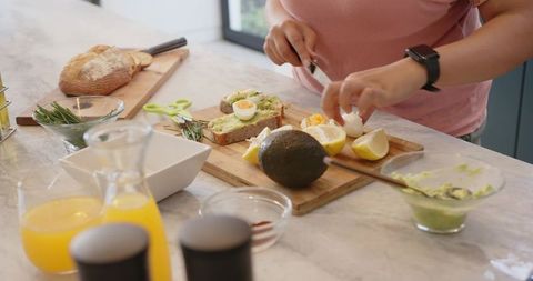 Preparing avocado toast with soft-boiled egg on marble counter, healthy breakfast idea