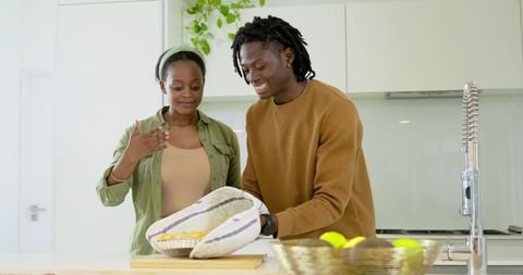 Smiling african american couple preparing homemade pie on minimalist kitchen island