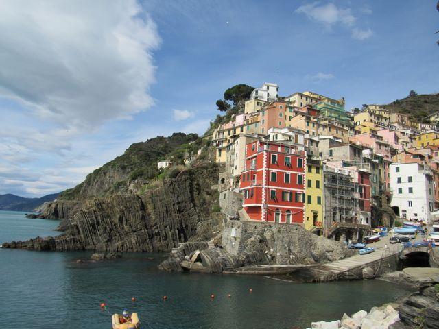 This vibrant depiction of houses perched on a cliffside in Riomaggiore, Italy, showcases the charm of Cinque Terre with its stunning ocean backdrop. Ideal for travel blogs, brochures, and travel promotional materials, it accentuates scenic beauty and architectural uniqueness.