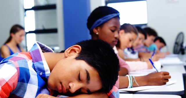 Students from diverse backgrounds are falling asleep at their desks during a lesson in a classroom. This can be used in contexts related to education, sleep deprivation, student life, or tiredness. It can illustrate issues such as the impact of long school hours on teenagers or the need for better engagement methods in teaching.