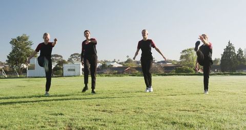 Dance Troupe Synchronizing High Kicks in Outdoor Park Performance