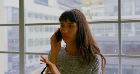 Businesswoman Engaged in Phone Call by Urban Window
